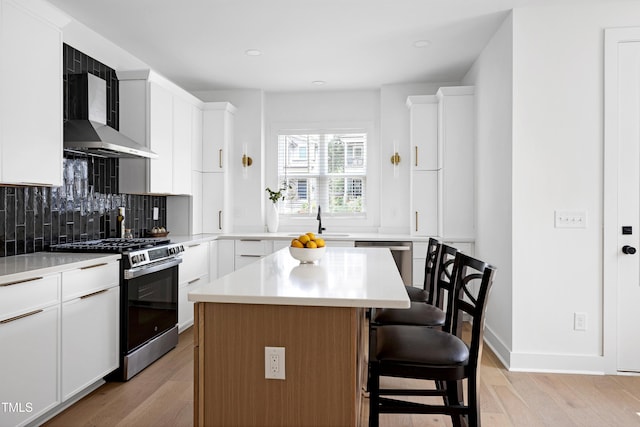 1410 Joe Louis Ave, Raleigh, NC 27610 - kitchen featuring appliances with stainless steel finishes, wall chimney exhaust hood, light wood-style floors, decorative backsplash, and a kitchen breakfast bar
