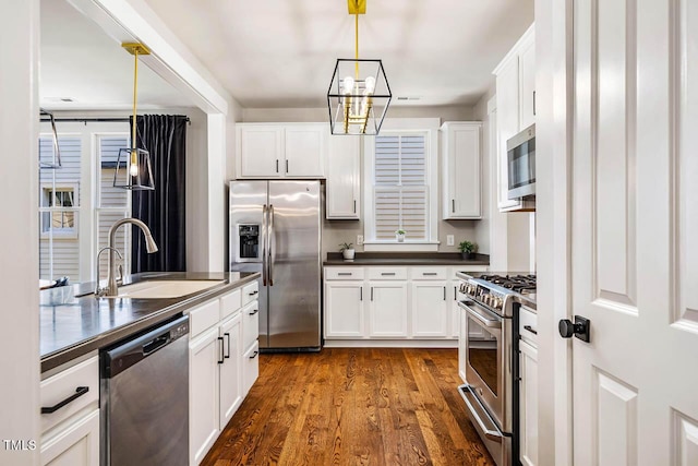 1168 Great Ridge Parkway, Chapel Hill, NC 27516 - kitchen with stainless steel appliances, dark countertops, dark wood-type flooring, a chandelier, and white cabinets