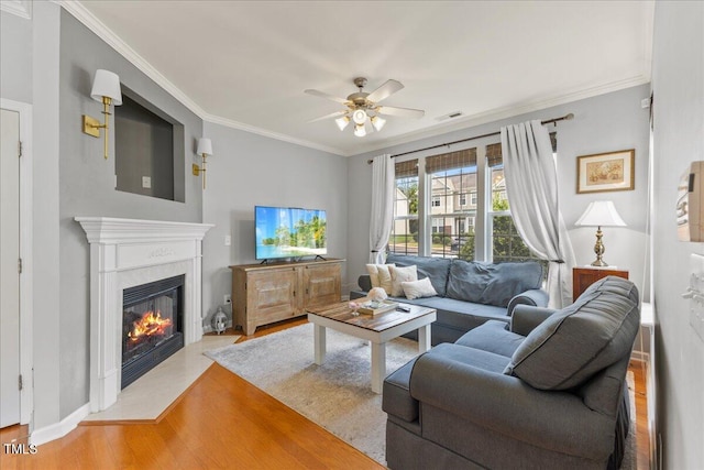 7856 Spungold St, Raleigh, NC 27617 - living room featuring a ceiling fan, wood finished floors, a glass covered fireplace, and crown molding