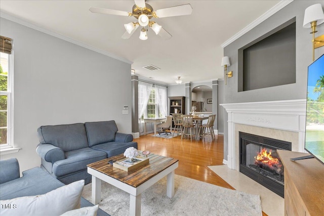 7856 Spungold St, Raleigh, NC 27617 - living room featuring arched walkways, ceiling fan, wood finished floors, a high end fireplace, and ornamental molding