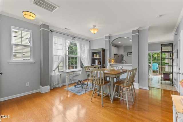 7856 Spungold St, Raleigh, NC 27617 - dining room featuring arched walkways, crown molding, and light wood finished floors