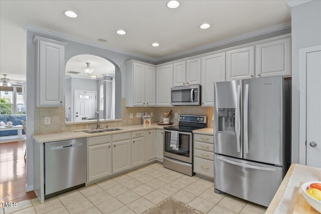 7856 Spungold St, Raleigh, NC 27617 - kitchen featuring stainless steel appliances, arched walkways, light countertops, decorative backsplash, and crown molding