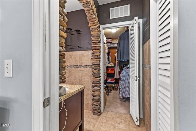 7856 Spungold St, Raleigh, NC 27617 - bathroom featuring a closet, vanity, tile patterned floors, and tile walls