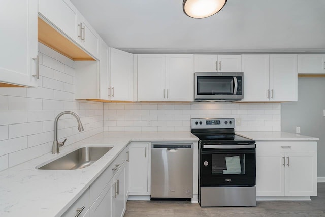 5917 Meadowlark Ln, Raleigh, NC 27610 - kitchen featuring appliances with stainless steel finishes, white cabinets, light wood-type flooring, light stone counters, and decorative backsplash