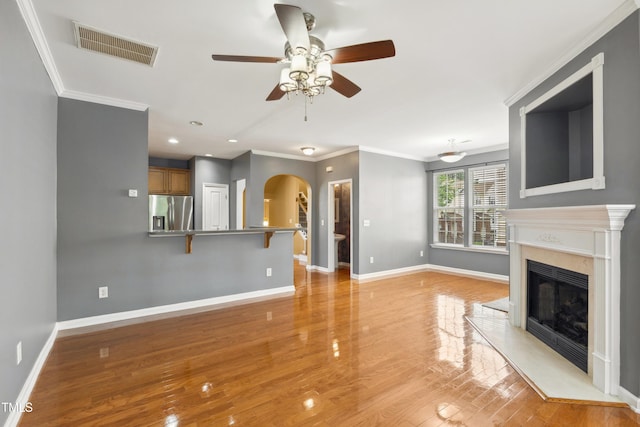 5503 Silver Moon Ln, Raleigh, NC 27606 - unfurnished living room featuring arched walkways, a ceiling fan, a fireplace, light wood-style flooring, and crown molding