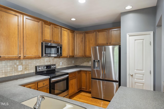 5503 Silver Moon Ln, Raleigh, NC 27606 - kitchen with stainless steel appliances, brown cabinetry, tasteful backsplash, recessed lighting, and light countertops