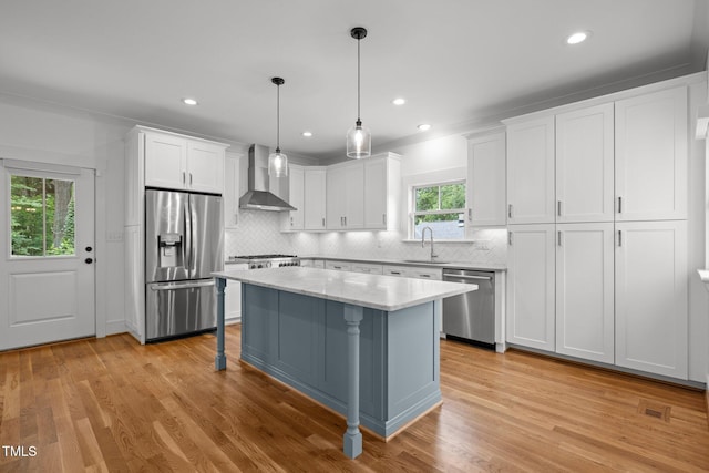 2551 Drake Ave, Durham, NC 27705 - kitchen with stainless steel appliances, wall chimney exhaust hood, white cabinetry, decorative backsplash, and light wood finished floors