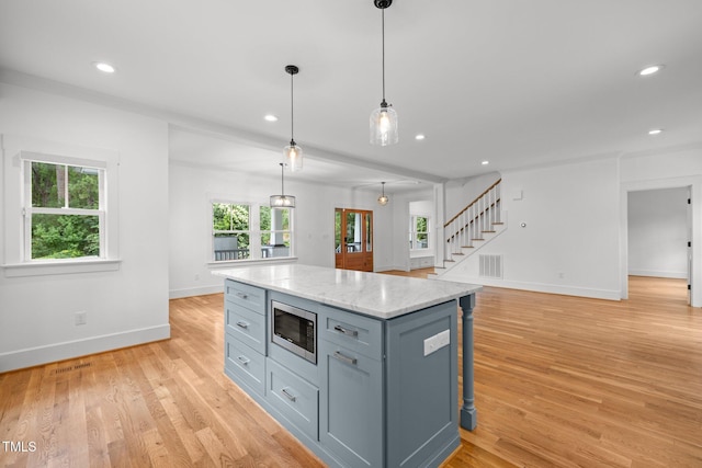 2551 Drake Ave, Durham, NC 27705 - kitchen featuring stainless steel microwave, light wood-style floors, a kitchen island, recessed lighting, and hanging light fixtures