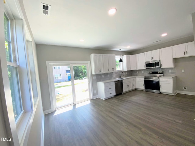 608A E Umstead, Durham, NC 27701 - kitchen featuring appliances with stainless steel finishes, light countertops, decorative backsplash, dark wood-style floors, and white cabinetry