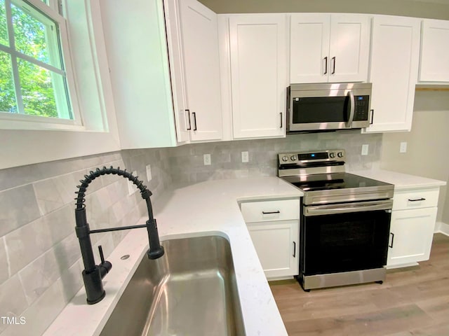 608A E Umstead, Durham, NC 27701 - kitchen with appliances with stainless steel finishes, light countertops, white cabinetry, decorative backsplash, and light wood-type flooring