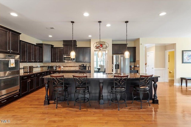150 Saint Mellion St, Raleigh, NC 27603 - kitchen featuring stainless steel appliances, a kitchen breakfast bar, dark brown cabinets, light wood-type flooring, and recessed lighting