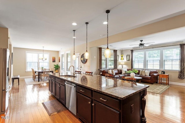 150 Saint Mellion St, Raleigh, NC 27603 - kitchen featuring appliances with stainless steel finishes, light wood-style floors, dark brown cabinets, dark stone counters, and hanging light fixtures
