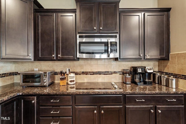 150 Saint Mellion St, Raleigh, NC 27603 - kitchen featuring stainless steel microwave, dark brown cabinetry, dark stone counters, and backsplash