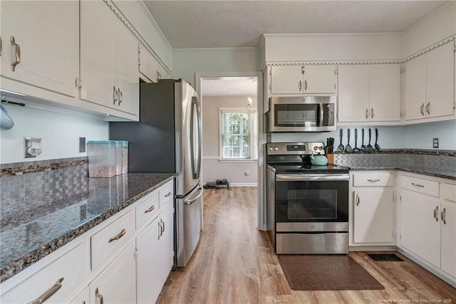 140 Bledsoe St, Hope Mills, NC 28348 - kitchen with stainless steel appliances, light wood-style flooring, ornamental molding, dark stone countertops, and white cabinets