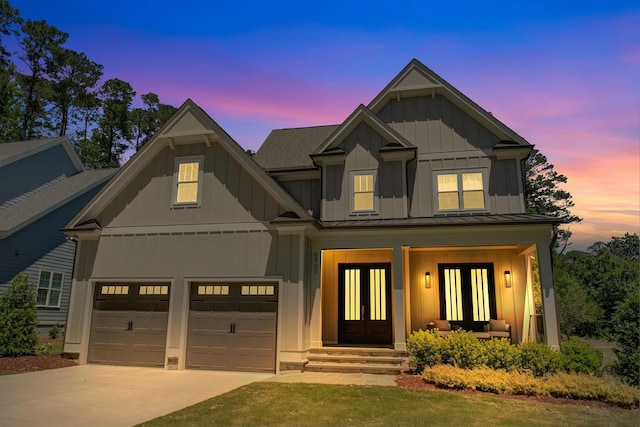 6900 Staghorn Ln, Raleigh, NC 27615 - view of front facade featuring french doors, board and batten siding, a standing seam roof, driveway, and an attached garage