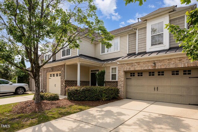 1016 Kingston Grove Dr, Cary, NC 27519 - townhome / multi-family property featuring a garage, concrete driveway, brick siding, a standing seam roof, and a metal roof