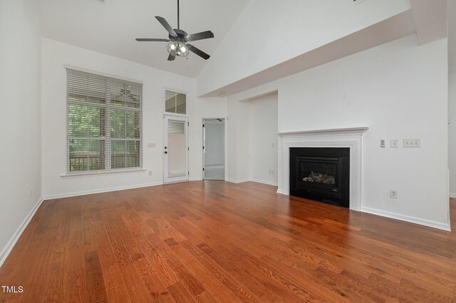 1016 Kingston Grove Dr, Cary, NC 27519 - unfurnished living room featuring wood finished floors, ceiling fan, a glass covered fireplace, and high vaulted ceiling