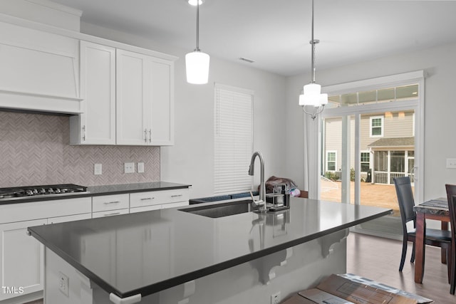 2346 Mckenzie Ridge Ln, Apex, NC 27502 - kitchen with a breakfast bar area, dark countertops, stainless steel gas cooktop, decorative backsplash, and white cabinets