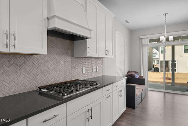 2346 Mckenzie Ridge Ln, Apex, NC 27502 - kitchen featuring custom range hood, stainless steel gas cooktop, dark countertops, tasteful backsplash, and wood finished floors
