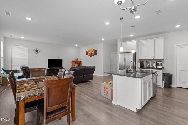 2346 Mckenzie Ridge Ln, Apex, NC 27502 - kitchen with stainless steel appliances, dark countertops, white cabinets, wood finished floors, and recessed lighting