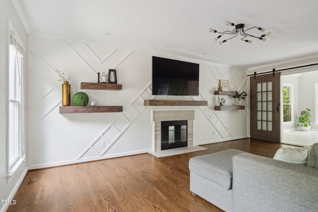 5809 N Hawthorne Way, Raleigh, NC 27603 - living room featuring ornamental molding, a barn door, wood finished floors, and a fireplace with flush hearth