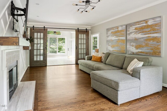 5809 N Hawthorne Way, Raleigh, NC 27603 - living area featuring ornamental molding, wood finished floors, a barn door, a chandelier, and a high end fireplace
