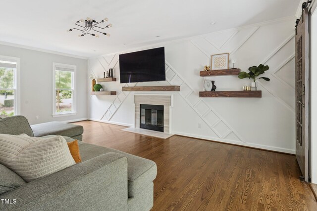 5809 N Hawthorne Way, Raleigh, NC 27603 - living room with a barn door, crown molding, wood finished floors, a fireplace with flush hearth, and a decorative wall