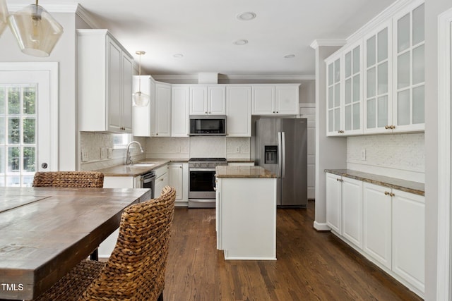 5809 N Hawthorne Way, Raleigh, NC 27603 - kitchen with stainless steel appliances, a kitchen island, glass insert cabinets, white cabinetry, and crown molding