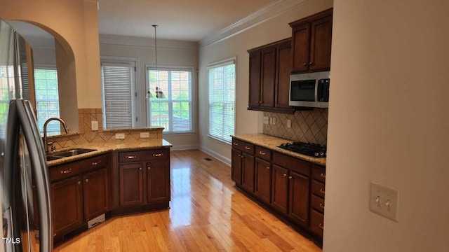 1016 Dotson Way, Apex, NC 27523 - kitchen with stainless steel microwave, freestanding refrigerator, black gas cooktop, arched walkways, and backsplash