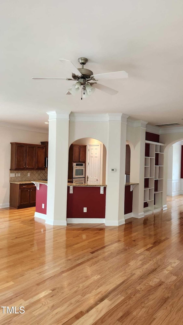 1016 Dotson Way, Apex, NC 27523 - unfurnished living room featuring arched walkways, ornamental molding, light wood-style floors, and a ceiling fan