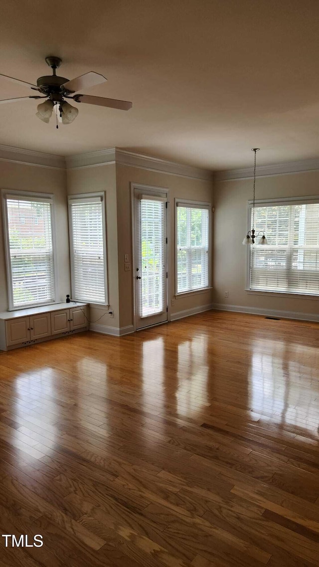 1016 Dotson Way, Apex, NC 27523 - unfurnished living room with ornamental molding, wood finished floors, a ceiling fan, and a chandelier