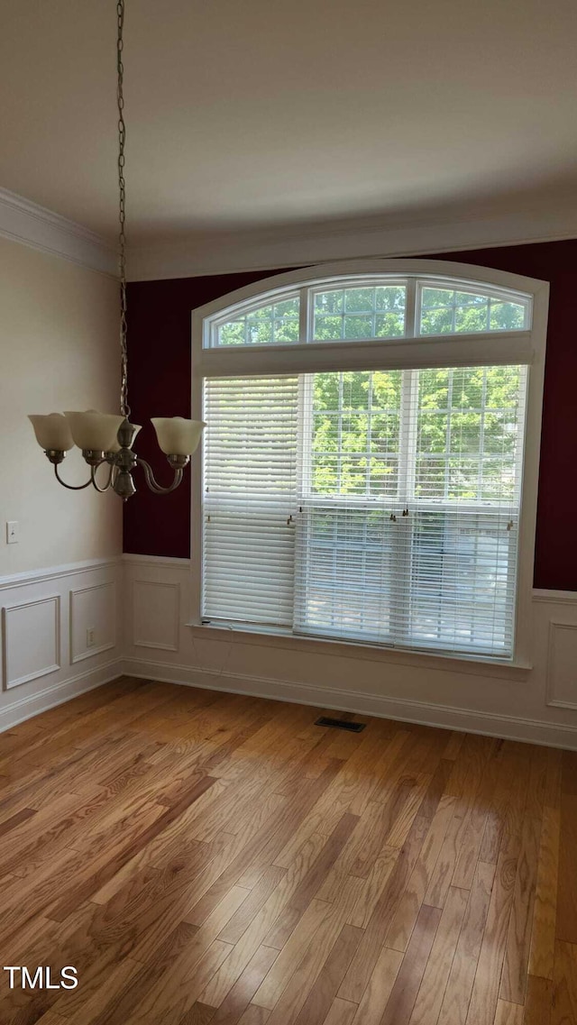 1016 Dotson Way, Apex, NC 27523 - unfurnished dining area featuring a chandelier, wainscoting, light wood-type flooring, crown molding, and a decorative wall
