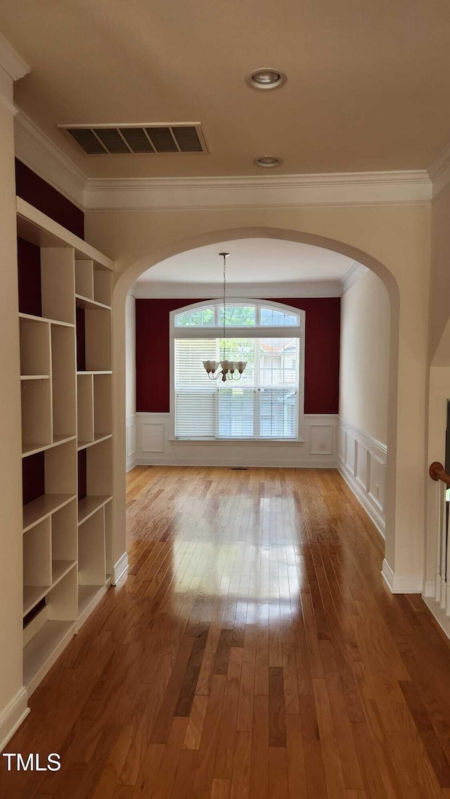 1016 Dotson Way, Apex, NC 27523 - hallway with ornamental molding, a chandelier, hardwood / wood-style flooring, a decorative wall, and arched walkways