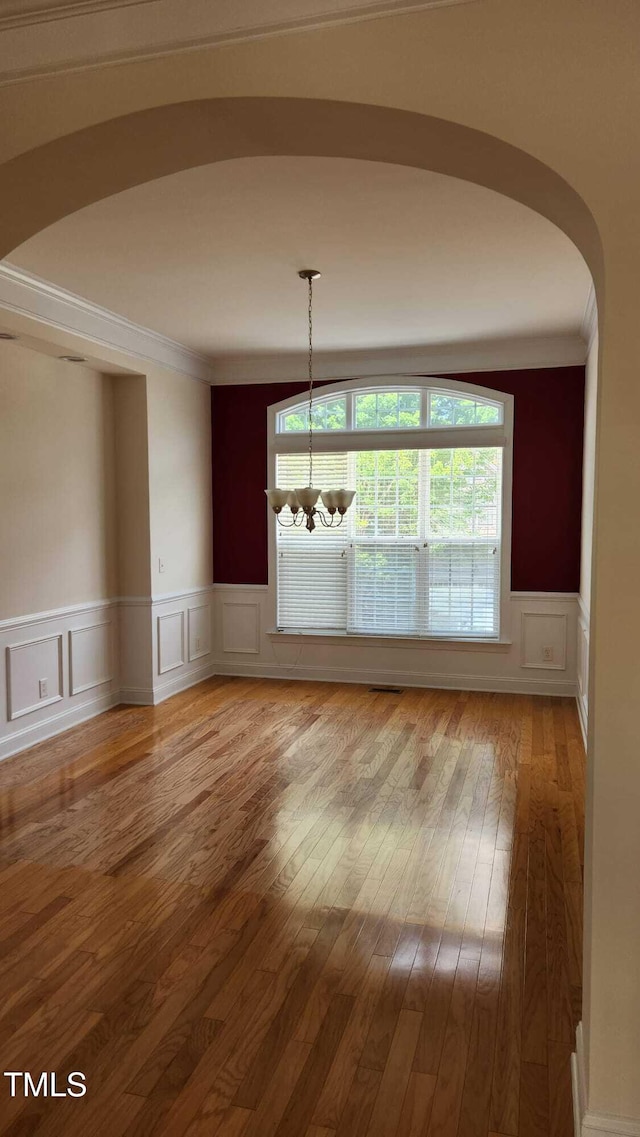 1016 Dotson Way, Apex, NC 27523 - unfurnished dining area with a chandelier, a decorative wall, hardwood / wood-style floors, wainscoting, and ornamental molding