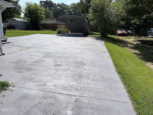 129 S Bullock St, Henderson, NC 27536 - view of patio featuring concrete driveway, a detached carport, and a storage shed