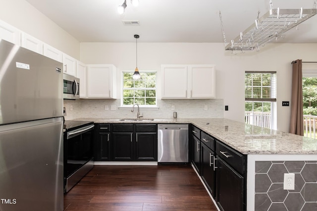 3110 Trinness Dr, Durham, NC 27707 - kitchen with stainless steel appliances, a peninsula, dark wood-style flooring, dark cabinets, and white cabinetry