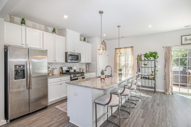 248 Amber Acorn Ave, Raleigh, NC 27603 - kitchen featuring stainless steel appliances, wood finished floors, tasteful backsplash, white cabinetry, and an island with sink