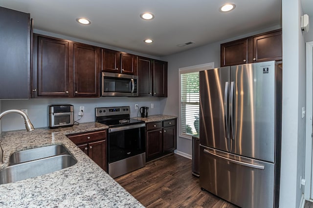 121 Longleaf Pine St, Clayton, NC 27527 - kitchen featuring appliances with stainless steel finishes, recessed lighting, dark brown cabinets, dark wood-style flooring, and light stone countertops