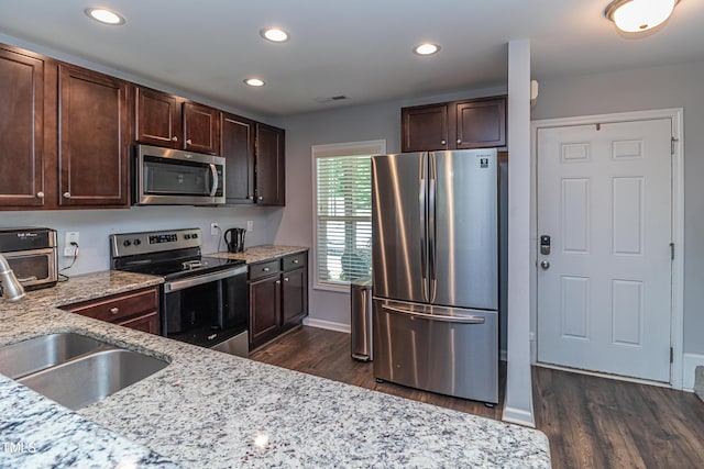 121 Longleaf Pine St, Clayton, NC 27527 - kitchen featuring appliances with stainless steel finishes, dark wood-type flooring, light stone counters, dark brown cabinetry, and recessed lighting