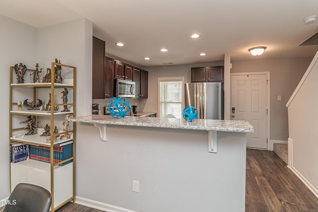 121 Longleaf Pine St, Clayton, NC 27527 - kitchen featuring stainless steel appliances, dark brown cabinets, a peninsula, a breakfast bar, and recessed lighting