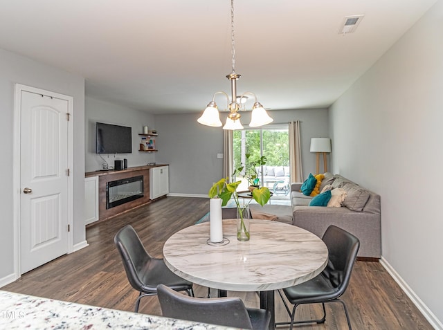 121 Longleaf Pine St, Clayton, NC 27527 - dining space with dark wood-style flooring, a chandelier, and a glass covered fireplace