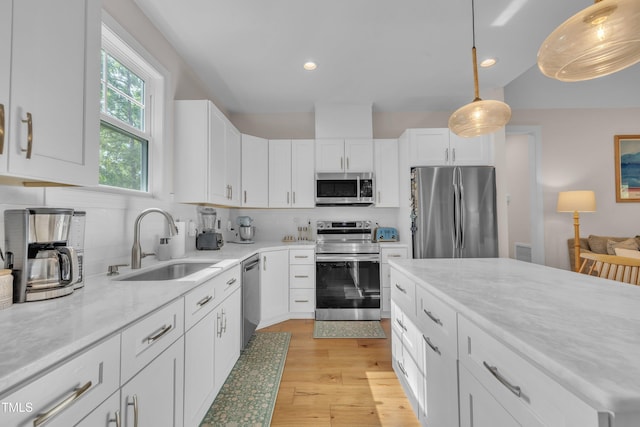 3909 Bristlewood Dr, Durham, NC 27703 - kitchen featuring stainless steel appliances, decorative backsplash, white cabinets, light wood finished floors, and decorative light fixtures