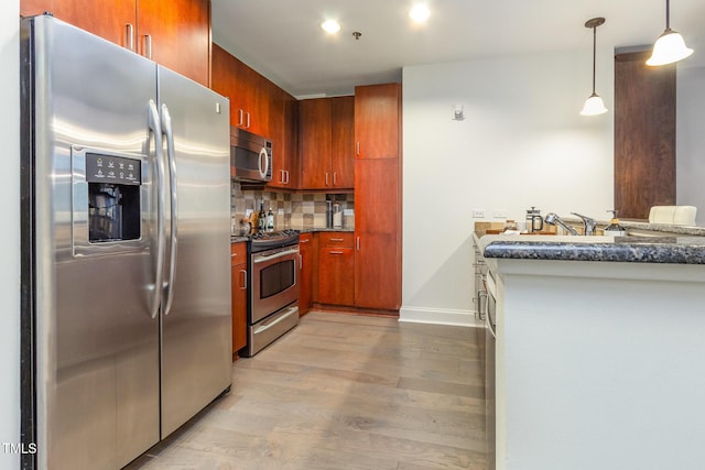 618 N Boylan Ave Unit 520, Raleigh, NC 27603 - kitchen featuring stainless steel appliances, wood finished floors, backsplash, pendant lighting, and brown cabinets