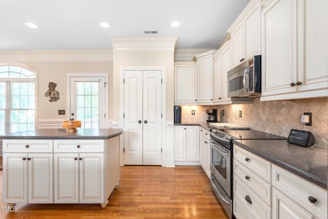 412 Whitt Ave, Burlington, NC 27215 - kitchen featuring appliances with stainless steel finishes, dark countertops, ornamental molding, a center island, and light wood-style floors