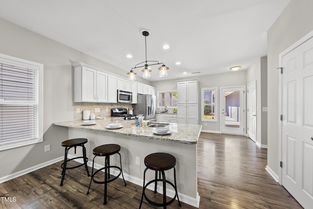 1625 Main Divide Dr, Wake Forest, NC 27587 - kitchen featuring stainless steel appliances, a peninsula, dark wood-style flooring, a kitchen bar, and recessed lighting