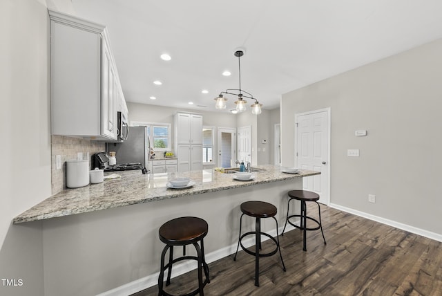 1625 Main Divide Dr, Wake Forest, NC 27587 - kitchen with a peninsula, dark wood-style floors, stove, light stone counters, and decorative backsplash