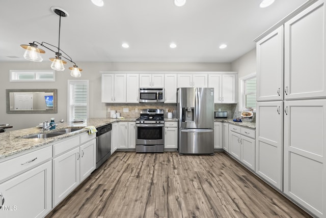 1625 Main Divide Dr, Wake Forest, NC 27587 - kitchen featuring stainless steel appliances, wood finished floors, white cabinetry, backsplash, and pendant lighting