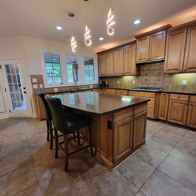 502 Willowmere Ct, Cary, NC 27513 - kitchen featuring a kitchen island, decorative backsplash, light tile patterned flooring, brown cabinets, and a breakfast bar