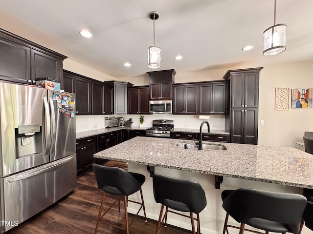 1005 Lathrop Ln, Apex, NC 27523 - kitchen with stainless steel appliances, dark wood-style flooring, light stone counters, pendant lighting, and dark brown cabinets