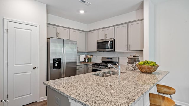 417 Belgian Red Way, Wake Forest, NC 27587 - kitchen with stainless steel appliances, gray cabinetry, a peninsula, and light stone countertops